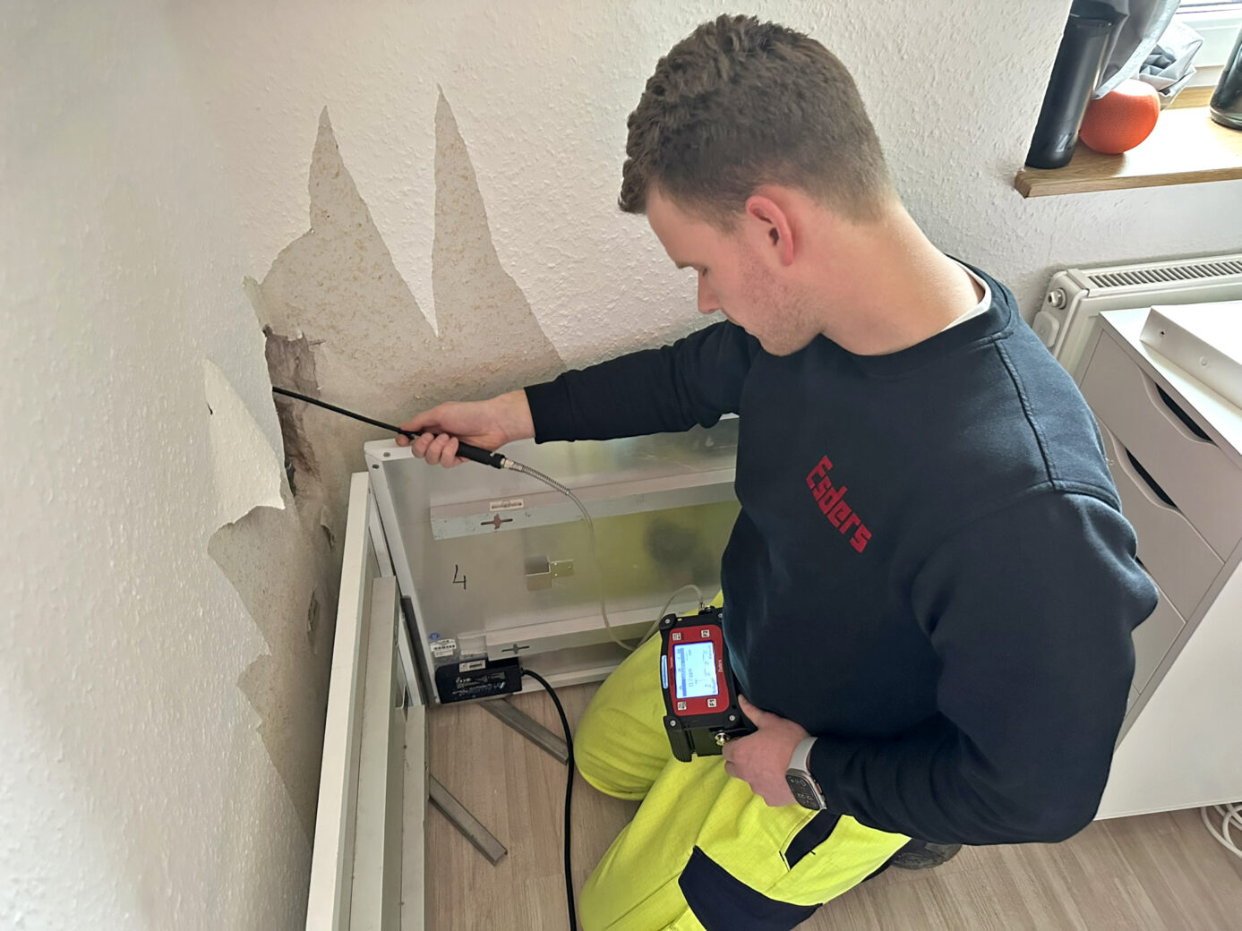 Persona buscando una fuga de agua dentro de una pared con un dispositivo de detección de fugas con gas trazador